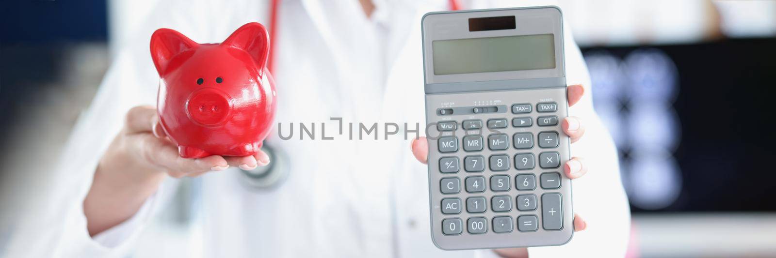 Doctor holding piggy bank and calculator by kuprevich
