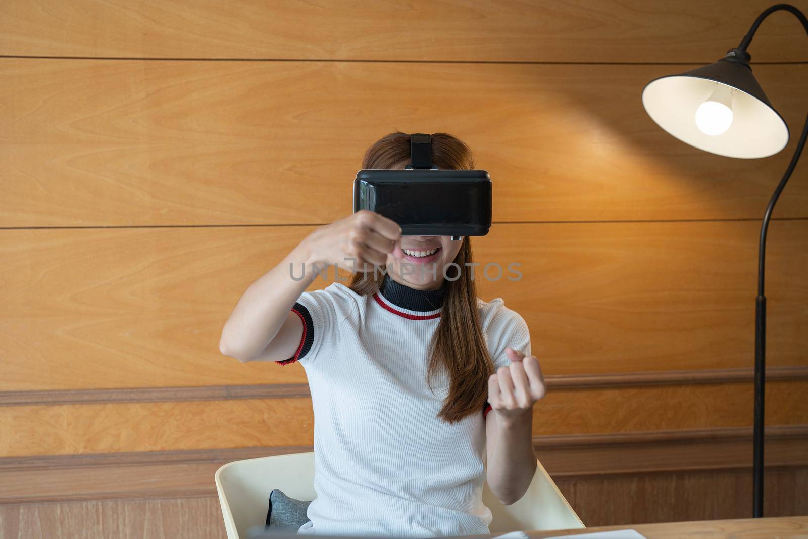 Excited young woman in VR goggles driving car in virtual reality. Lady screaming when turning virtual steering wheel, teen playing in racing computer game or road simulator,