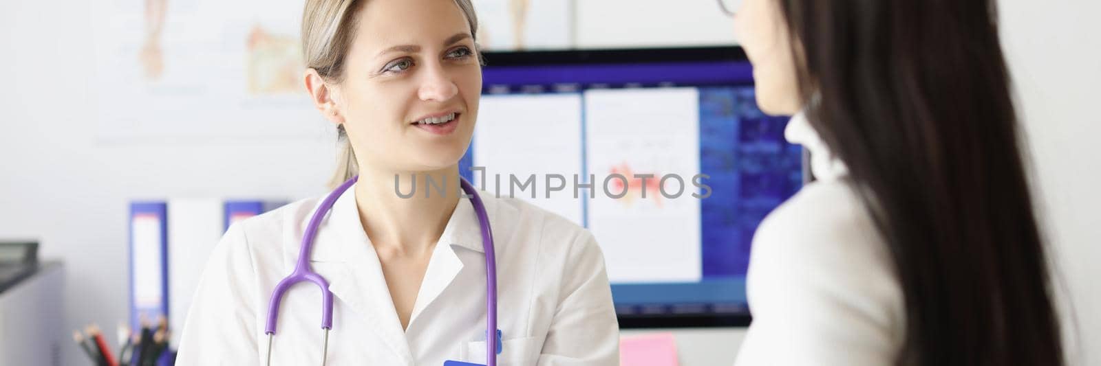 Portrait of smiling physician looking at woman patient with happiness. Good news about recovery. Routine examination by therapist. Doctors consultation idea. Healthcare and medicine concept