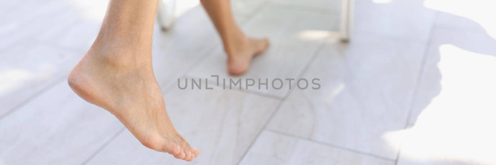 Close-up of persons feet step on tile near pool, barefoot man with hairy legs. Tanned body skin, enjoy summer vacation, hot days. Holiday, resort, summertime, chill concept
