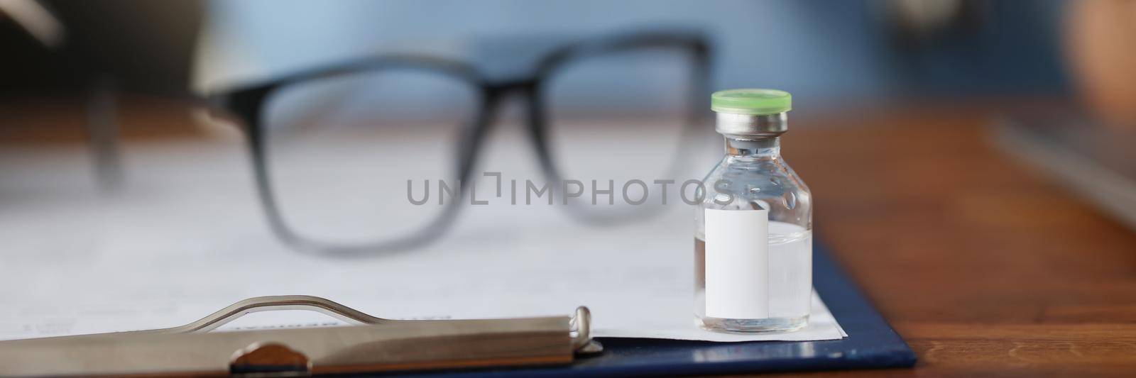 Glass bottle with vaccine on table by kuprevich