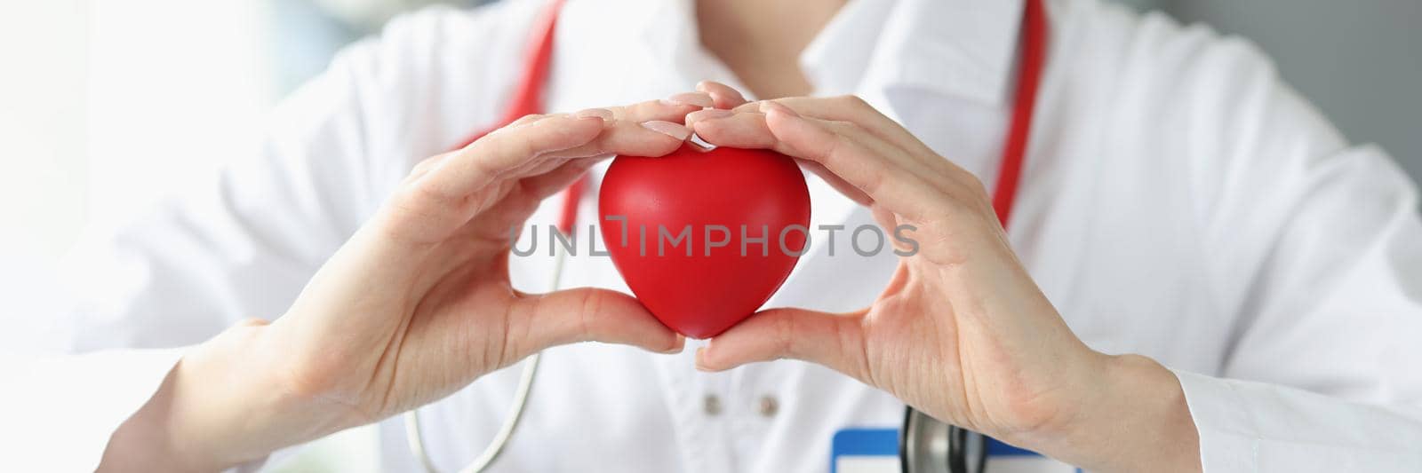 Close-up of cardiologist holding heart in hands. Treatment and healing with professional nurse and doctors. Heart disease, organ donation and cardiology concept
