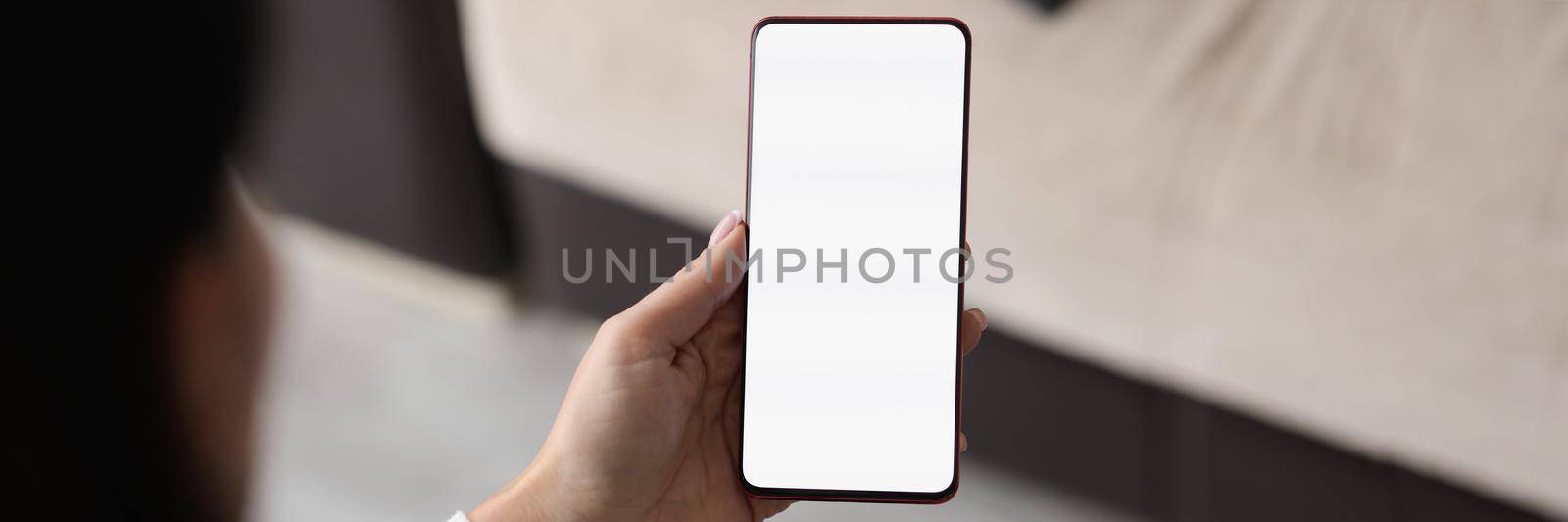 Close-up of female hand holding cellphone with blank display. Woman searching information in internet. Advertisement concept. Copy space on phone screen