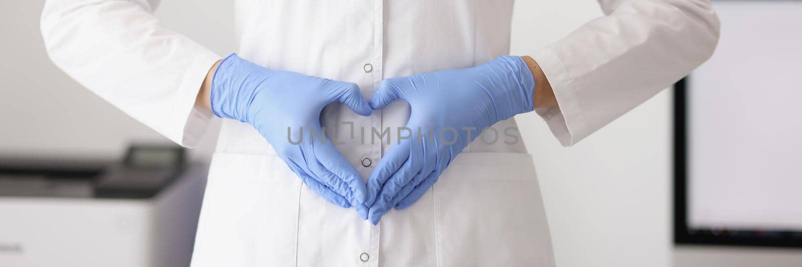 Close-up of female practitioner forming heart symbol with hands near belly. Pregnancy, motherhood and new life idea. Childbearing, carrying baby and gynecology concept