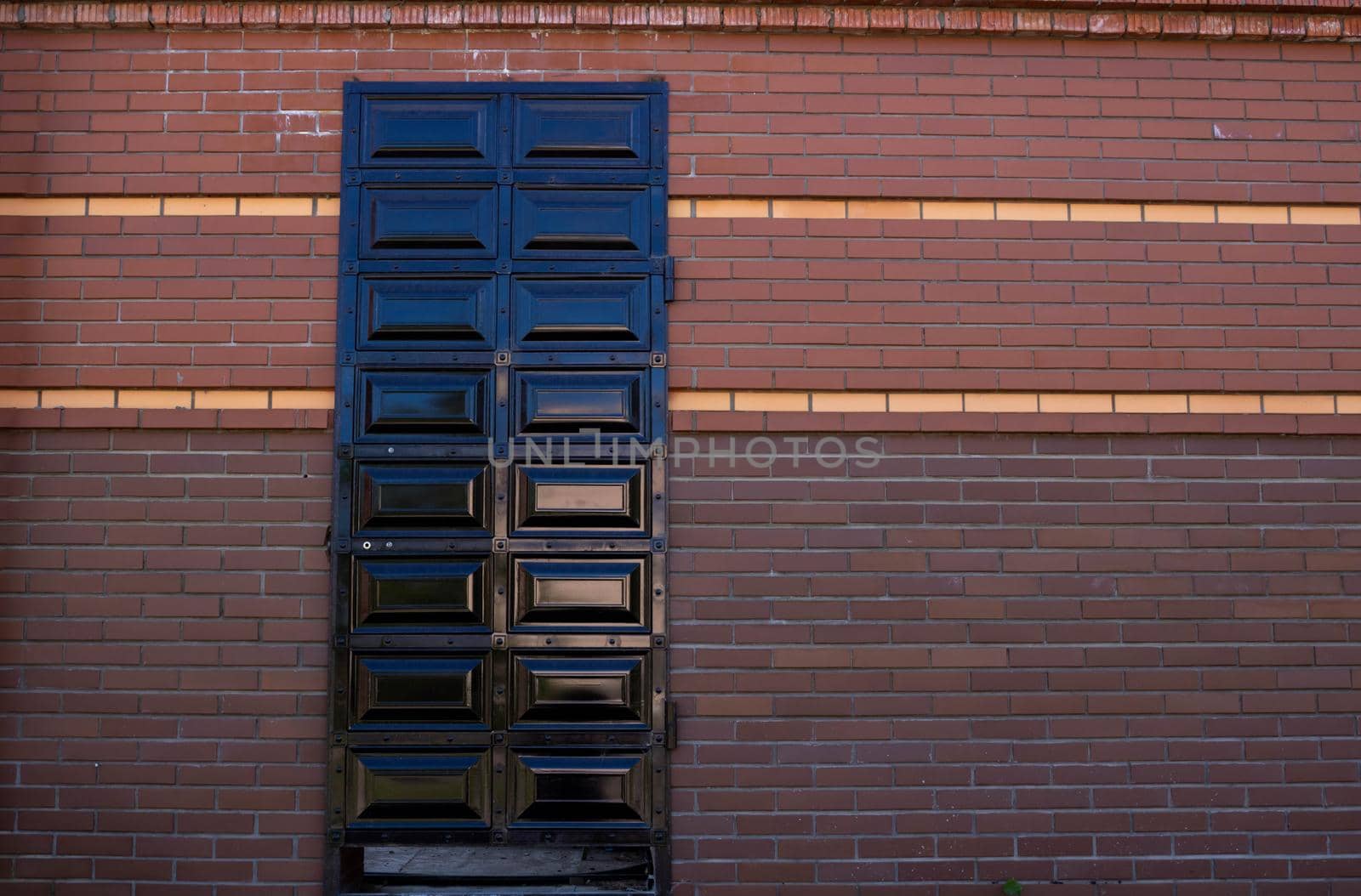 A locked iron door is installed in a red brick wall.