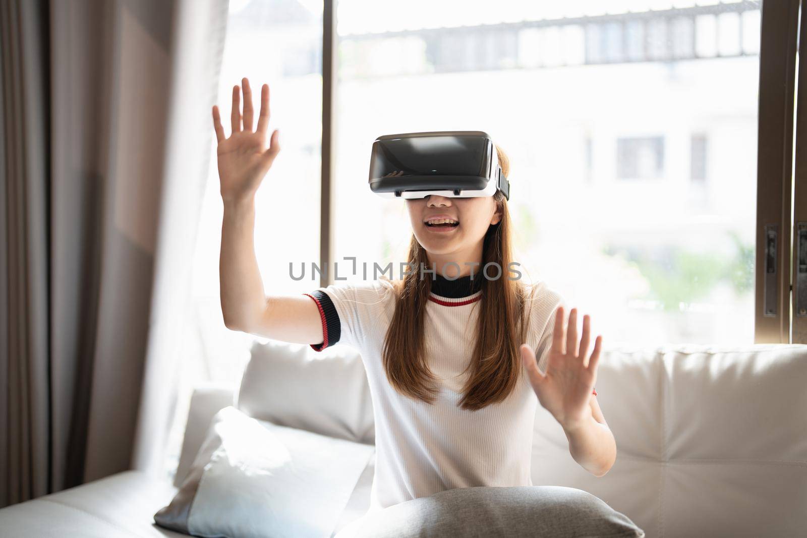 Excite asian woman playing online game with vr glasses and controller at her home.