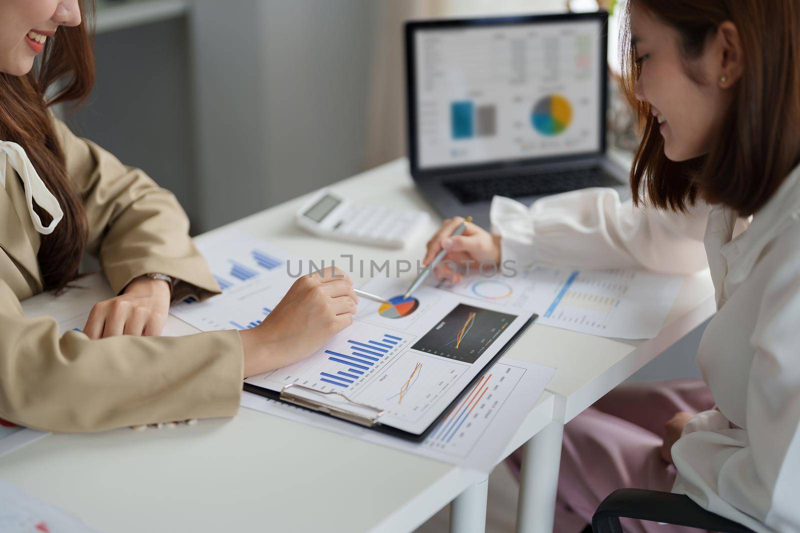 Two asian business woman are meeting for analysis data figures to plan business strategies. Business discussing concept.