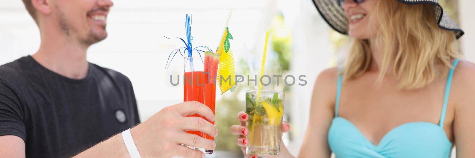 Portrait of friendly man and woman met each other in bar on holiday, drinking cooling cocktails, share interests. Summer romance, date, vacation, resort, summertime concept