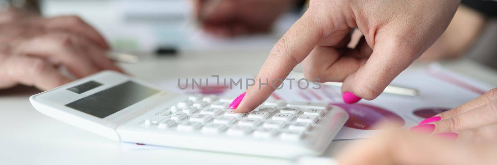 Close-up of woman with pink nails calculate profit, press on number knobs. Mess on working desk, work in process, solve financial problems. Business, economy, banking concept