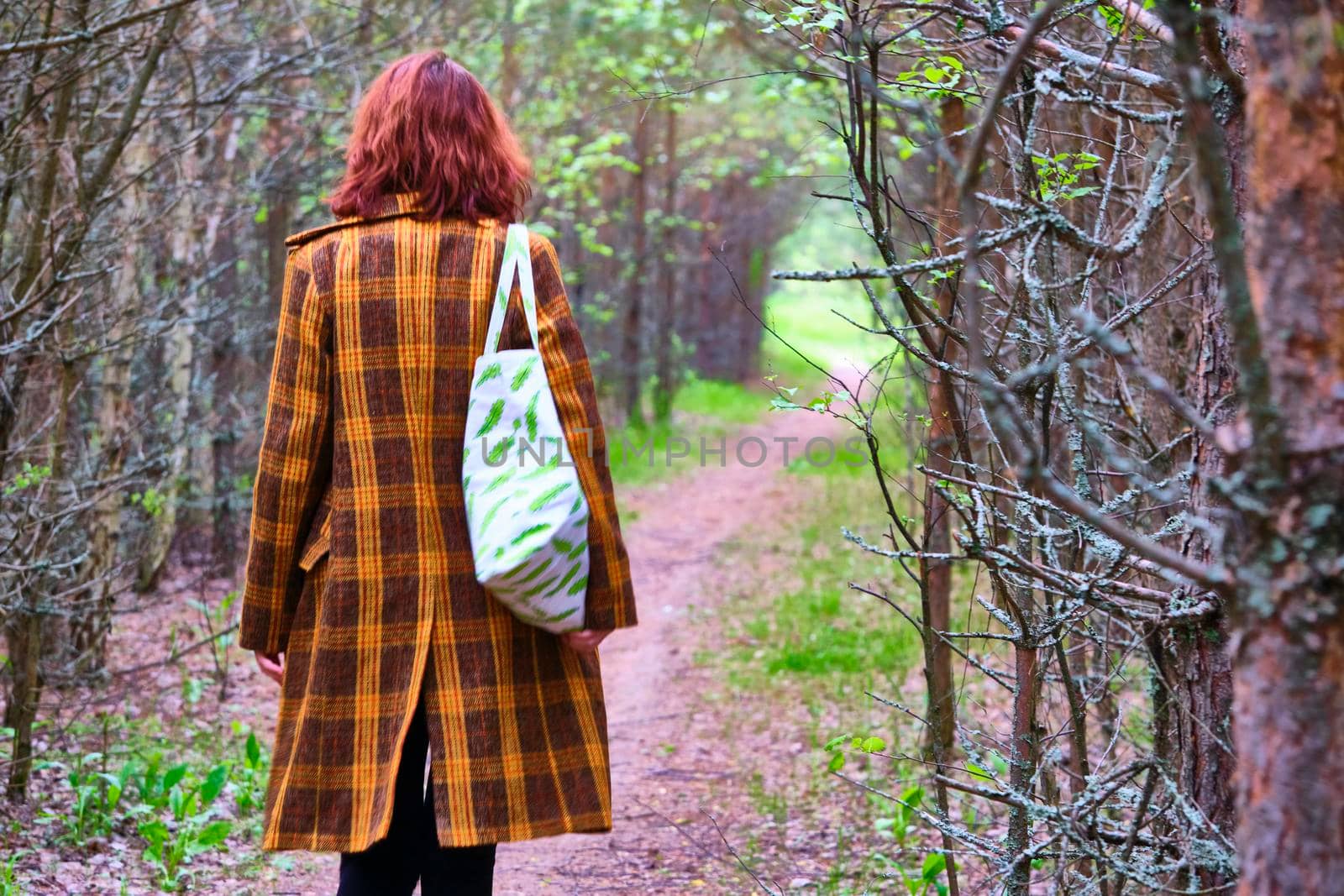 Girl in a coat walks through the woods , selective focus