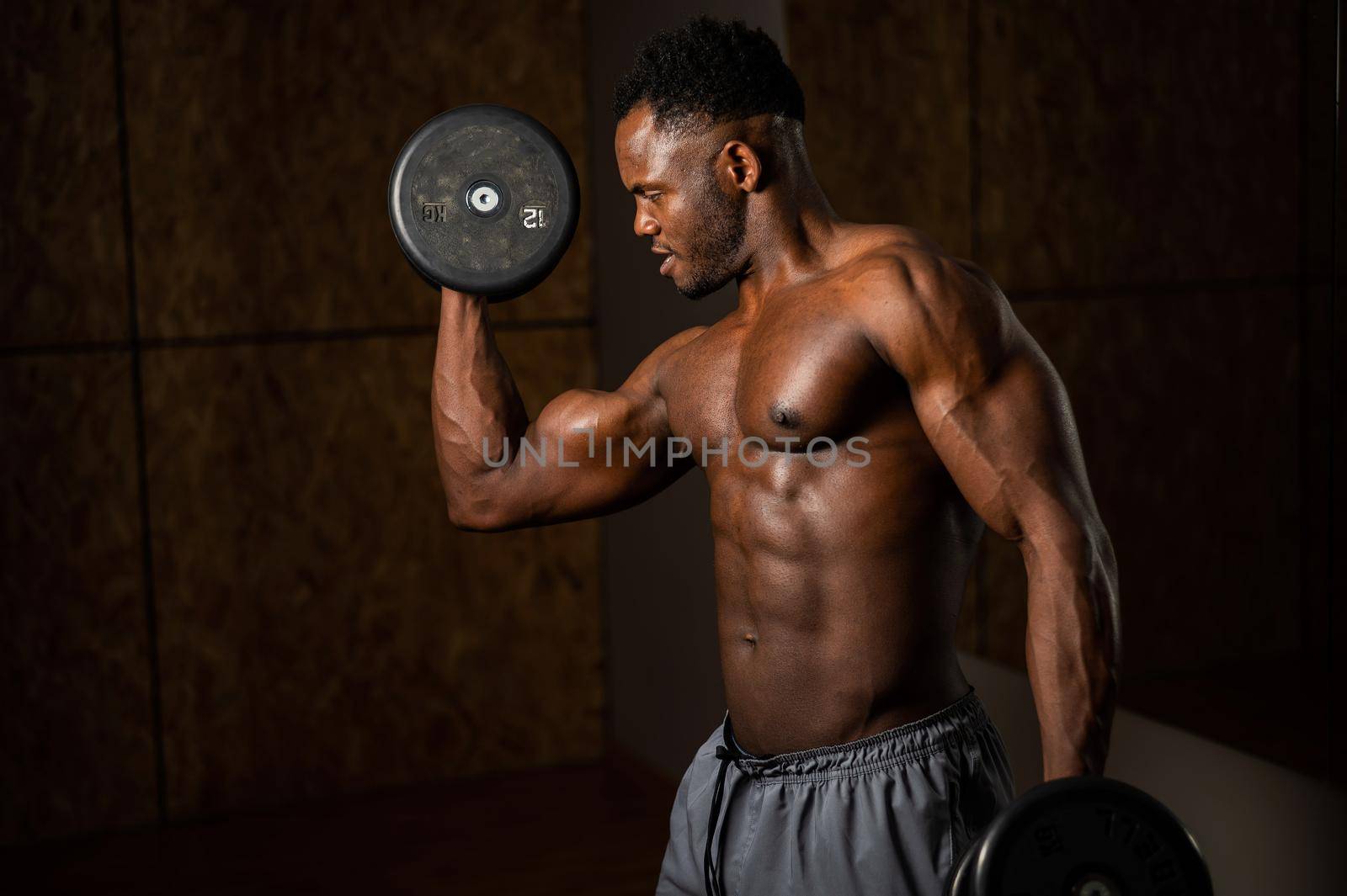 Attractive african american man smiling and doing exercise with dumbbells. by mrwed54