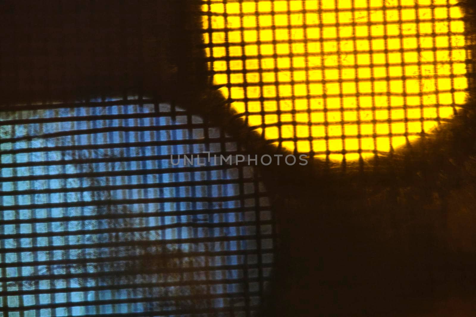 abstraction of lights behind metal mesh low light