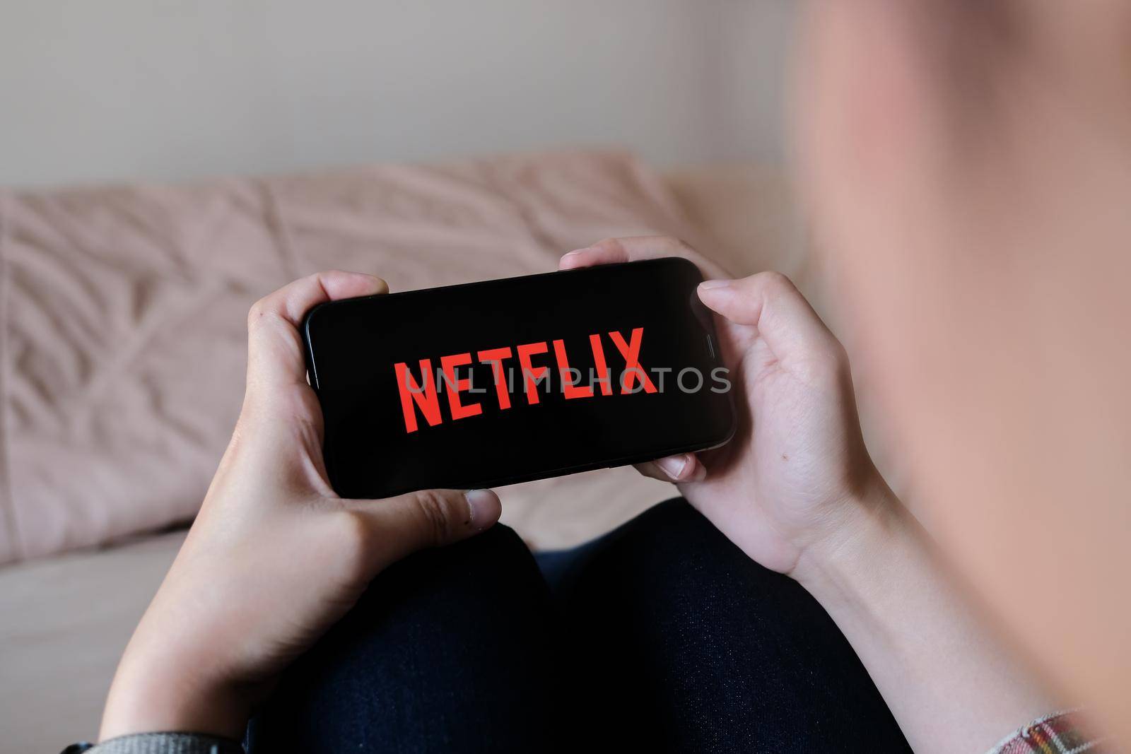 CHIANG MAI, THAILAND, MAR 29, 2020: Woman hand holding Smart Phone with Netflix logo on Apple iPhone Xs at home. by nateemee