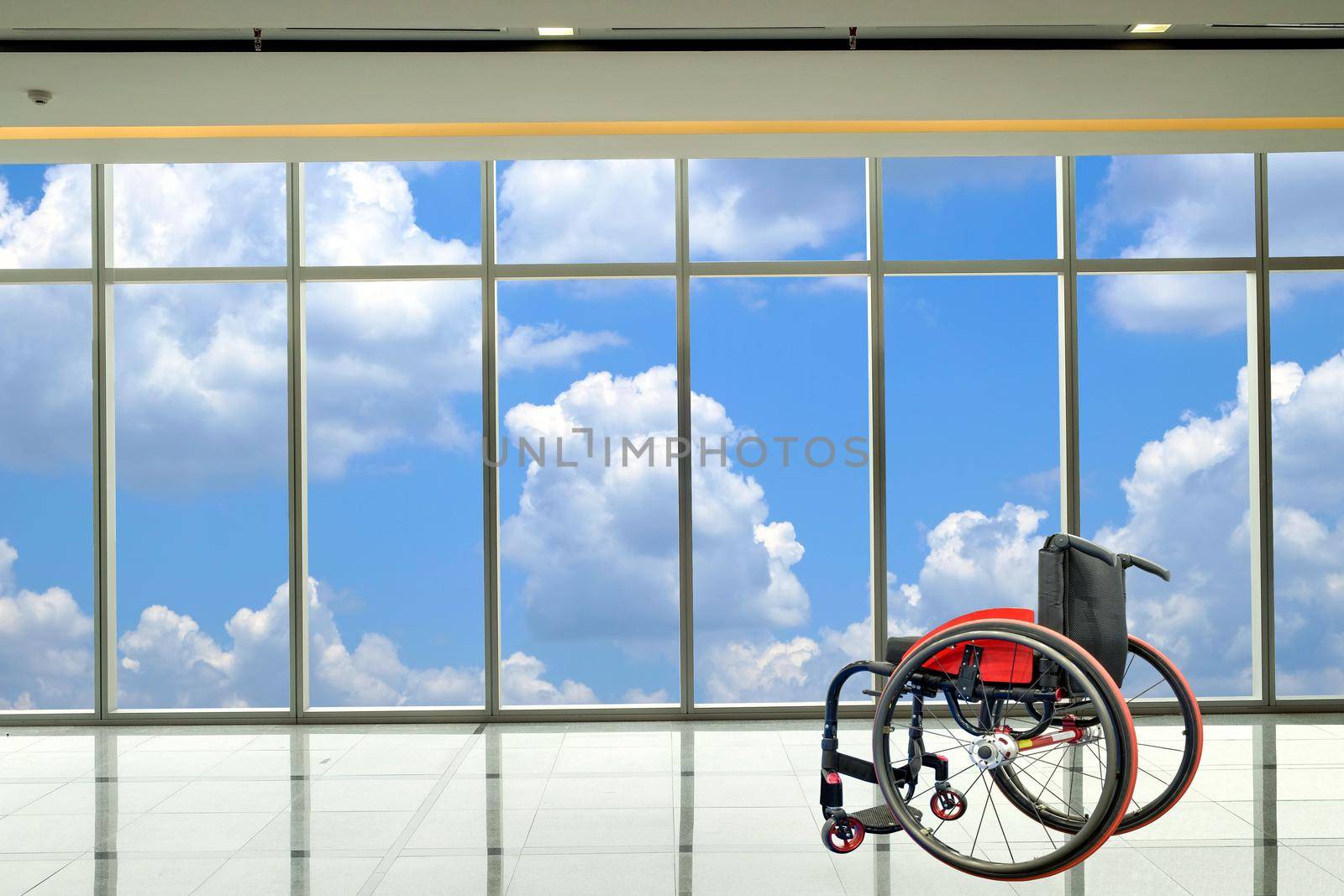 Modern wheelchair parked in empty room with cloud and sky background, healthcare and medical concept