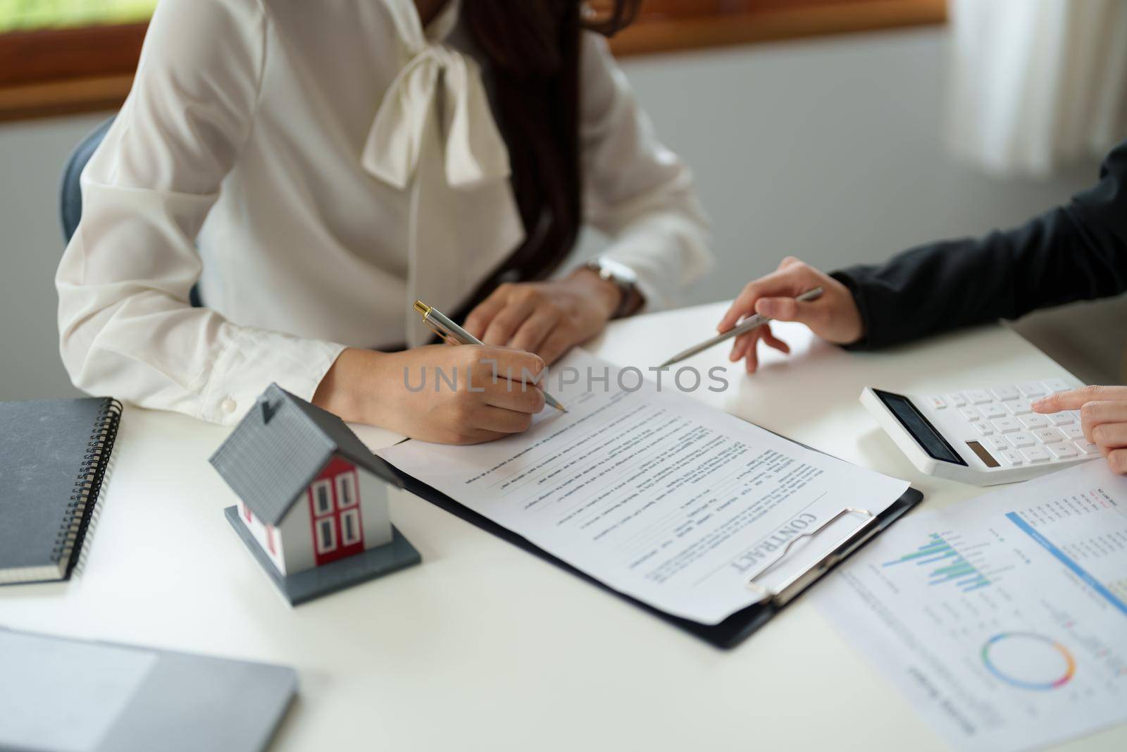 experienced real estate agent showing house model to client and ready to sign contract.