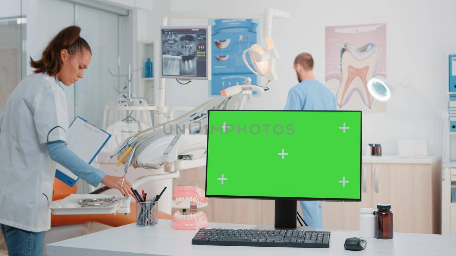 Horizontal green screen on computer in dental cabinet while dentist and assistant using oral care equipment for stomatological examination. Monitor with chroma key and isolated mockup template