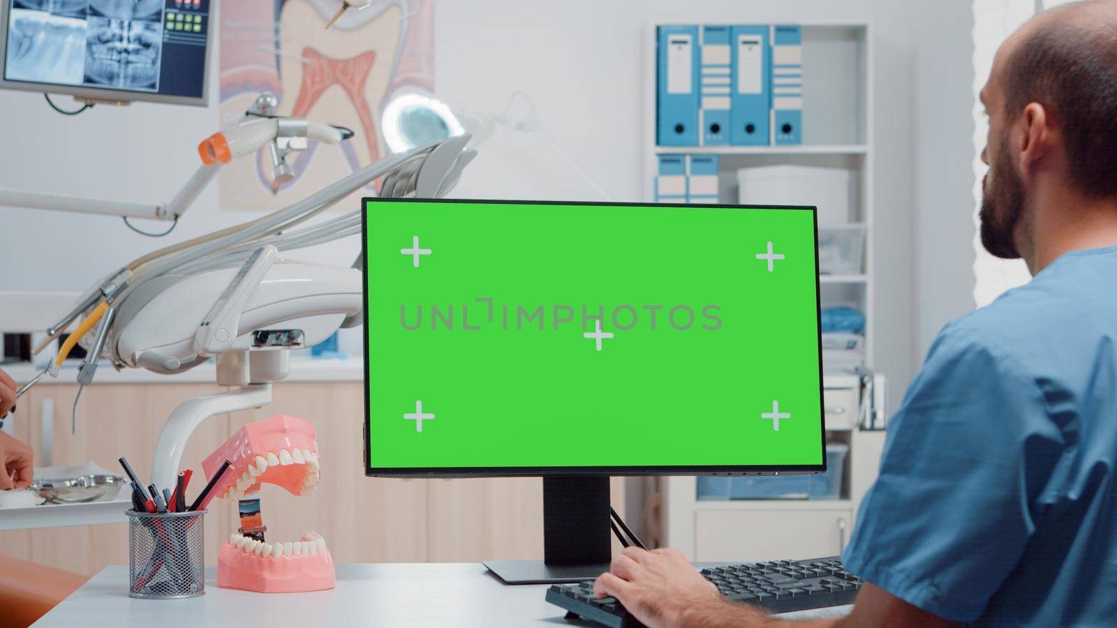 Man nurse looking at horizontal green screen on monitor by DCStudio