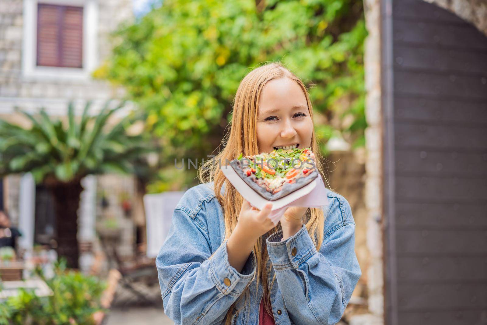 Young woman tourist eating traditional pizza in the old town of Budva. Travel to Montenegro concept by galitskaya