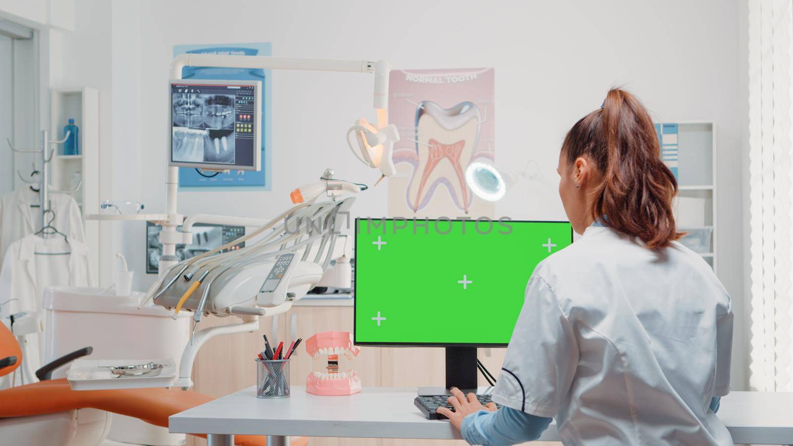 Dentist using computer with horizontal green screen on display by DCStudio
