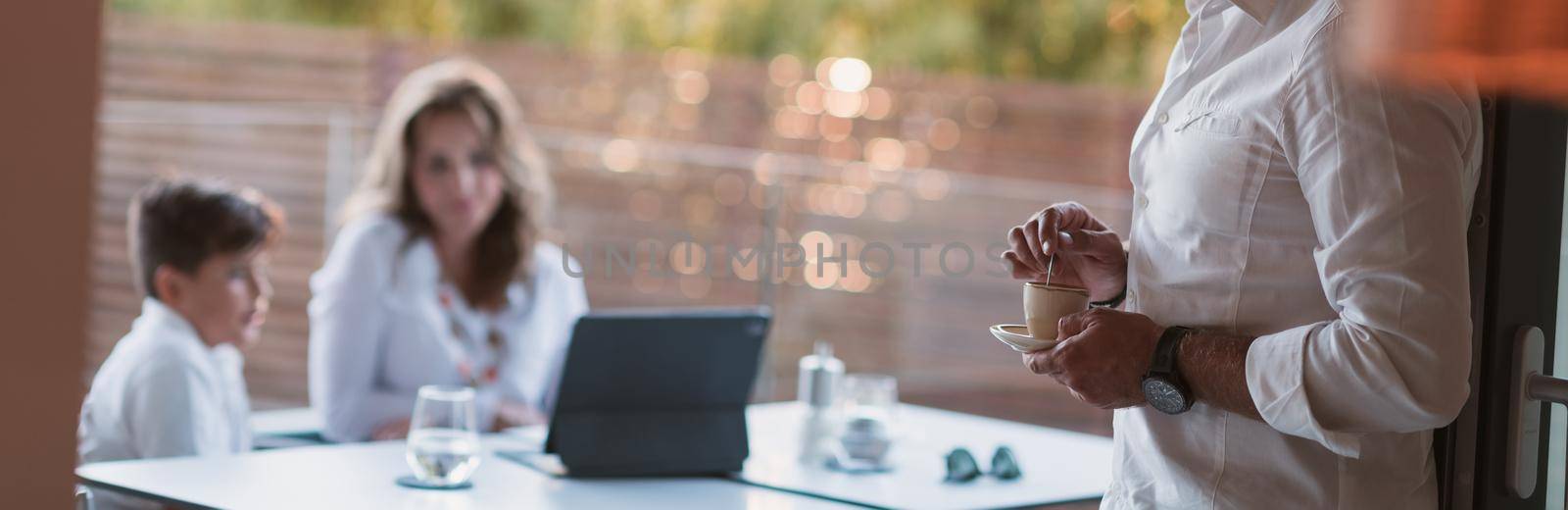 An elderly couple enjoys the terrace of a luxury house with their son during the holidays. Selective focus. High-quality photo