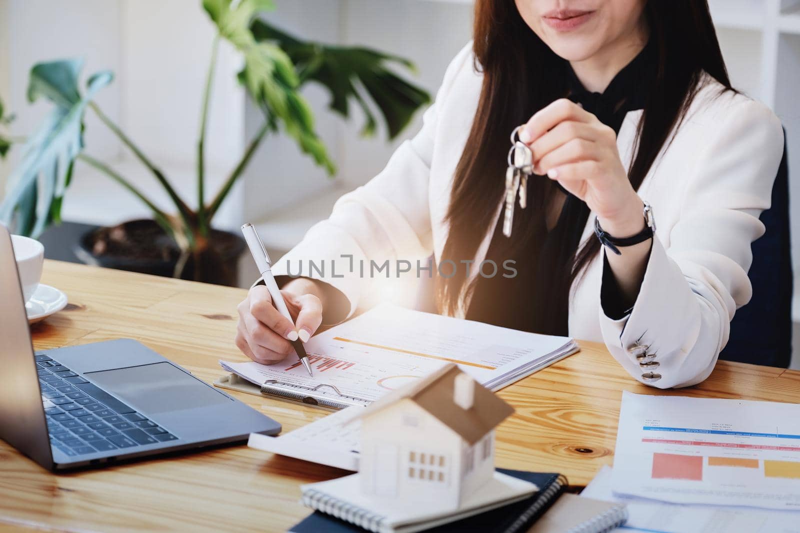 Asian woman accountant, business woman, real estate agent, holding a pen, pointing at home loan and interest documents to calculate the risk in the home investment budget. by Manastrong