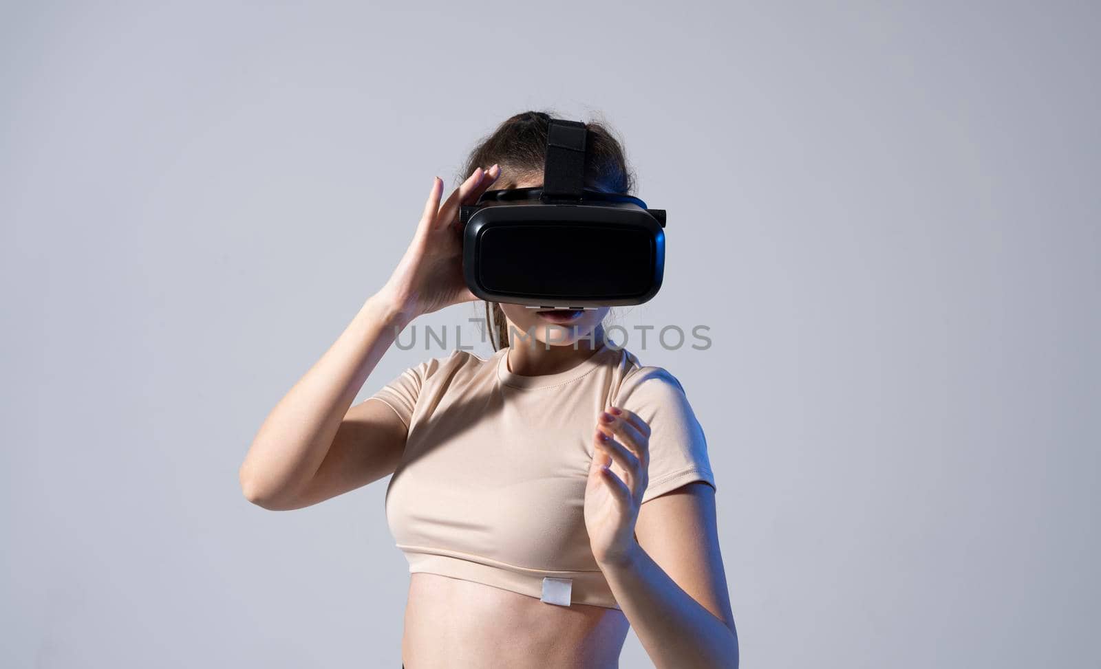 Young brunette woman wearing a virtual reality headset goggles and playing a game with a friends in metaverse. Future technology concept