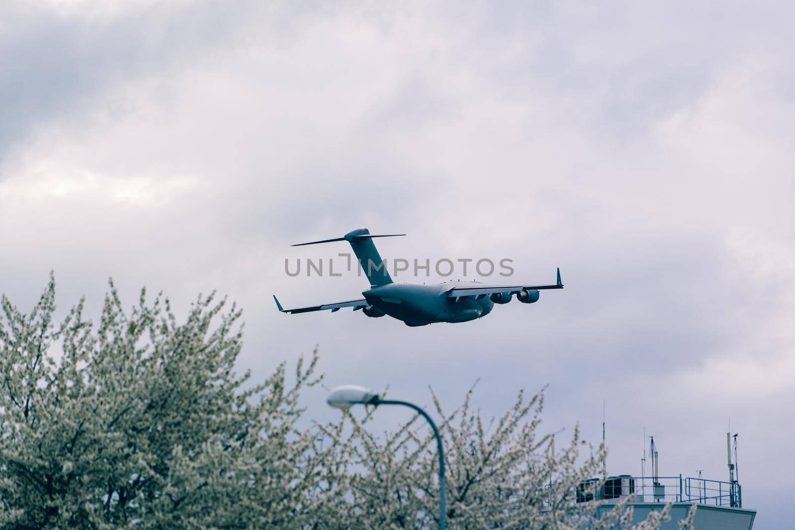 Big grey plane taking off from airport. Control tower in a flowering trees by Ashtray25