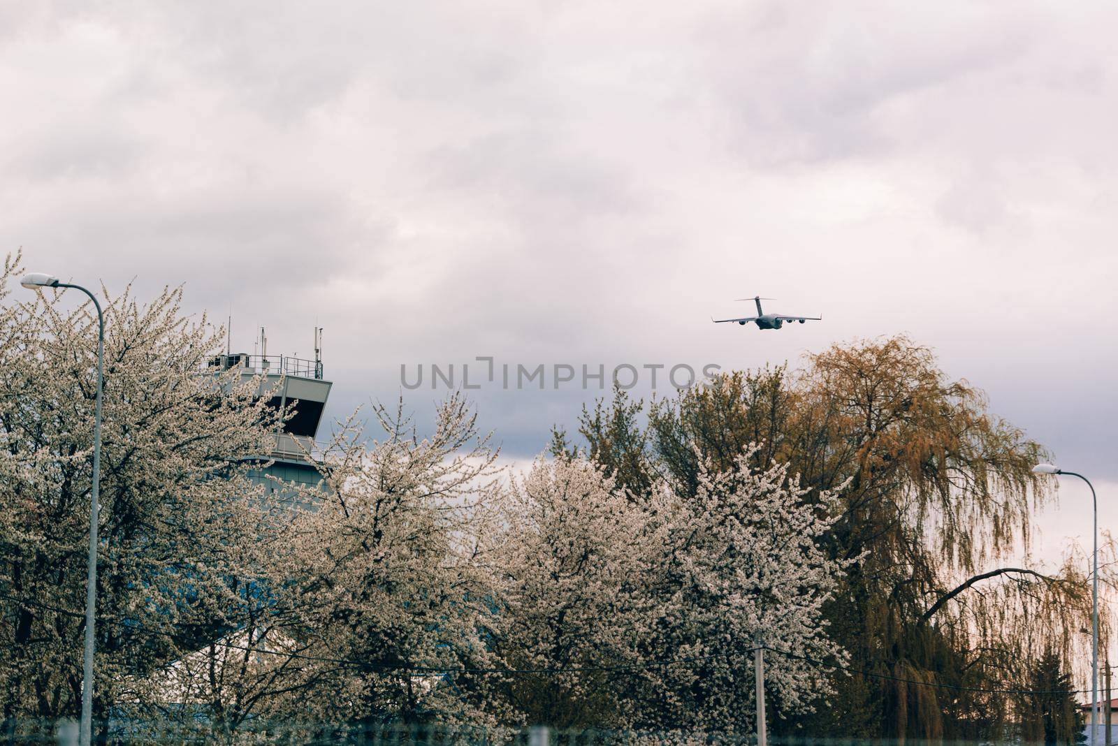 Big grey plane taking off from airport. Control tower in a flowering trees by Ashtray25