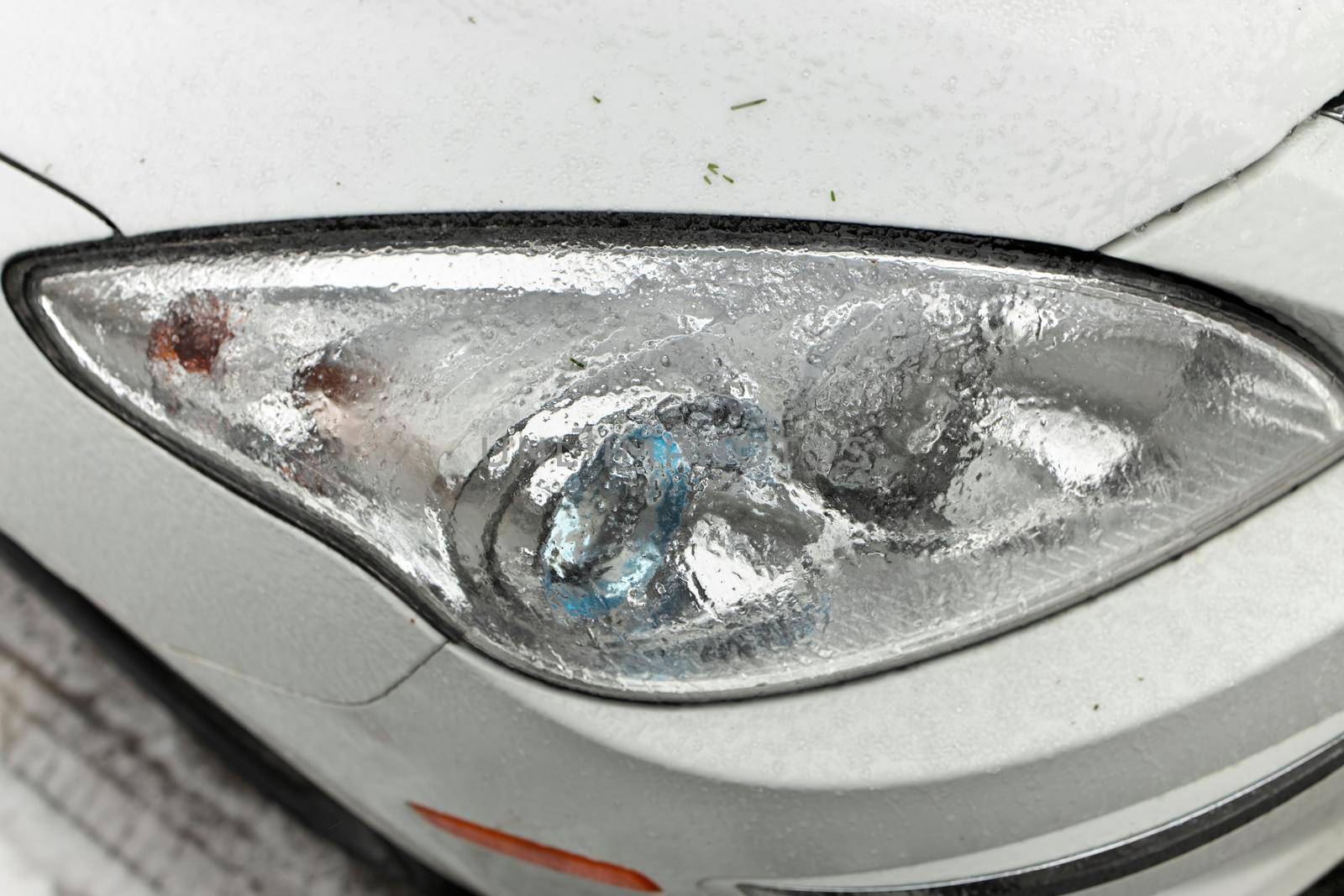 Freezing Rain Creates a Layer of Ice and Coats a Passenger Vehicle. Close up of Headlights by markvandam