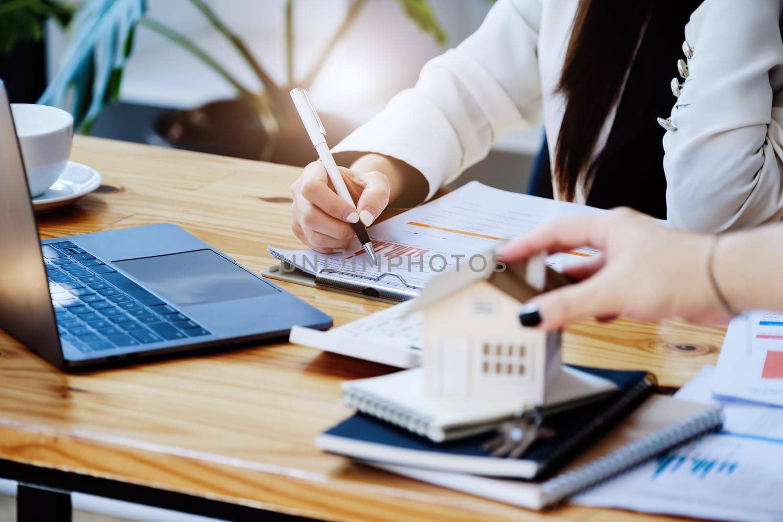 Asian woman accountant, business woman, real estate agent, holding a pen, pointing at home loan and interest documents to calculate the risk in the home investment budget. by Manastrong