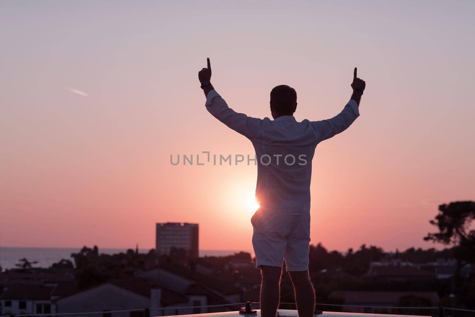 an elderly businessman in casual clothes enjoys the roof of his house at sunset time. Selective focus by dotshock