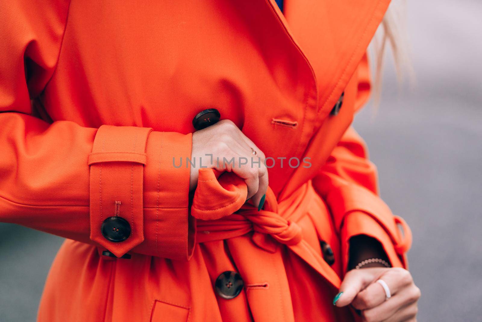 Fashionable blonde woman wearing orange coat, blue jeanse , white sneackers and neckchain posing in street by Ashtray25