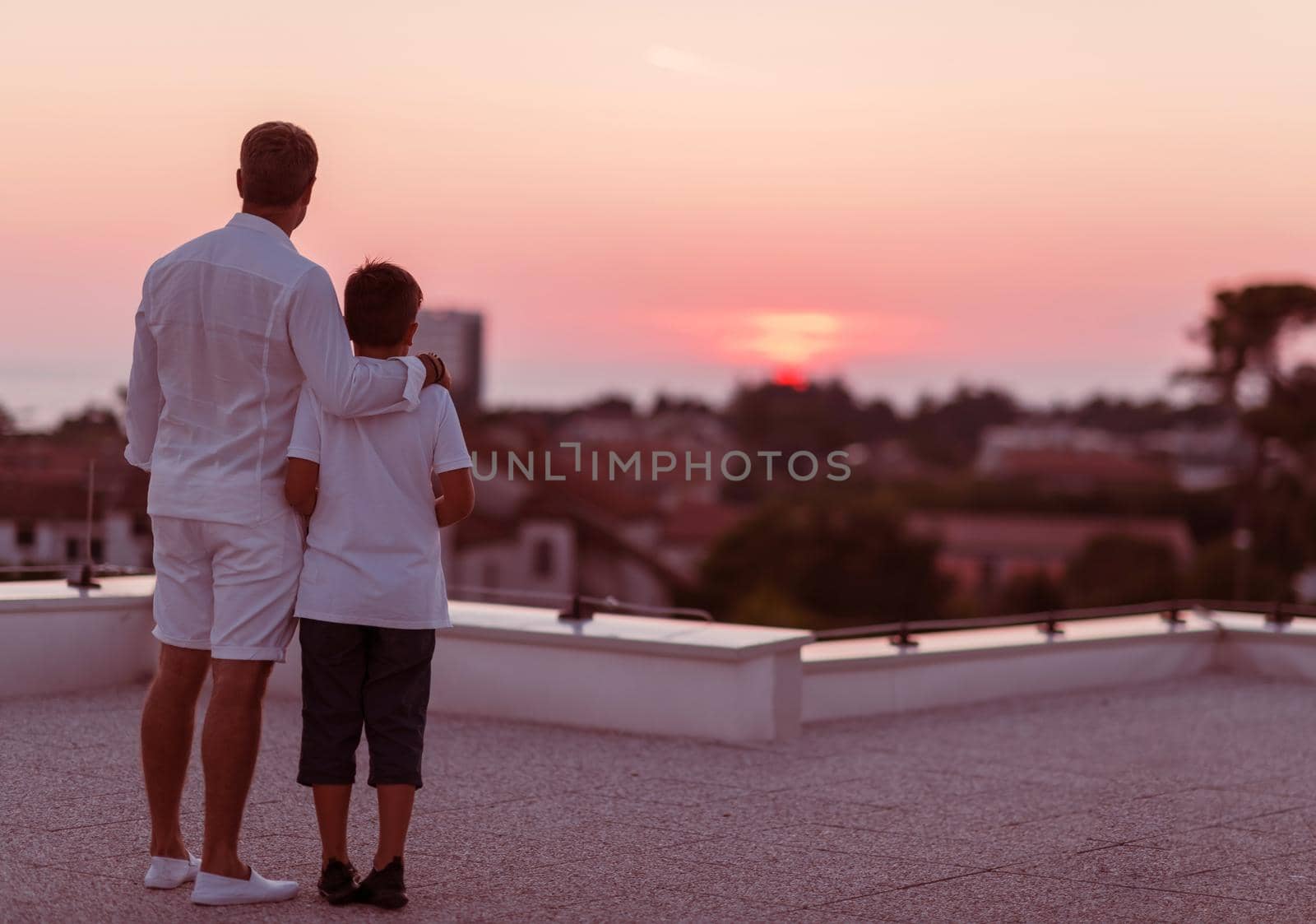 Father and son spend time together on the roof of the house while enjoying the sunset. Selective focus by dotshock