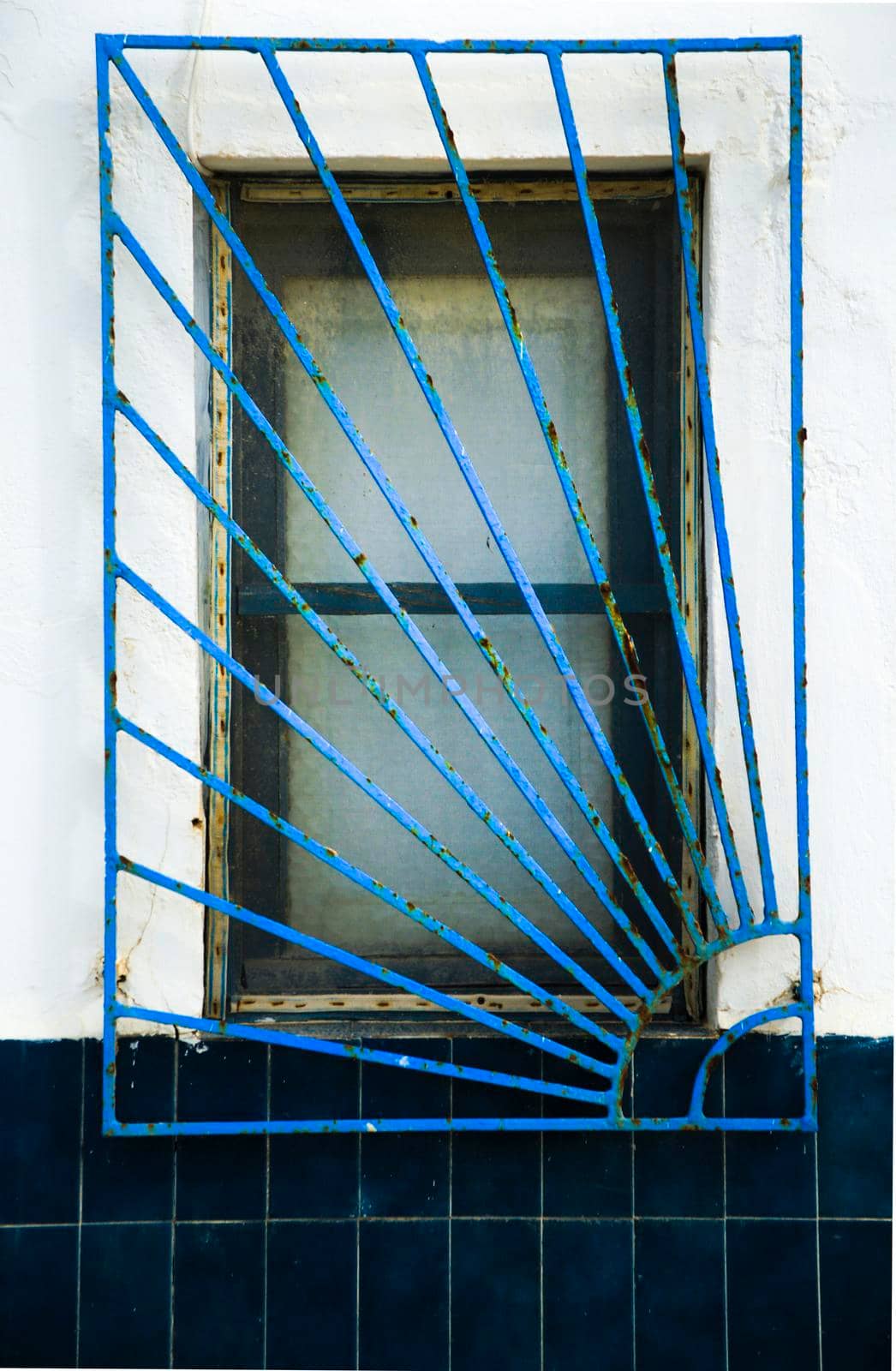Blue wooden window with blue geometric iron lattice in Spain