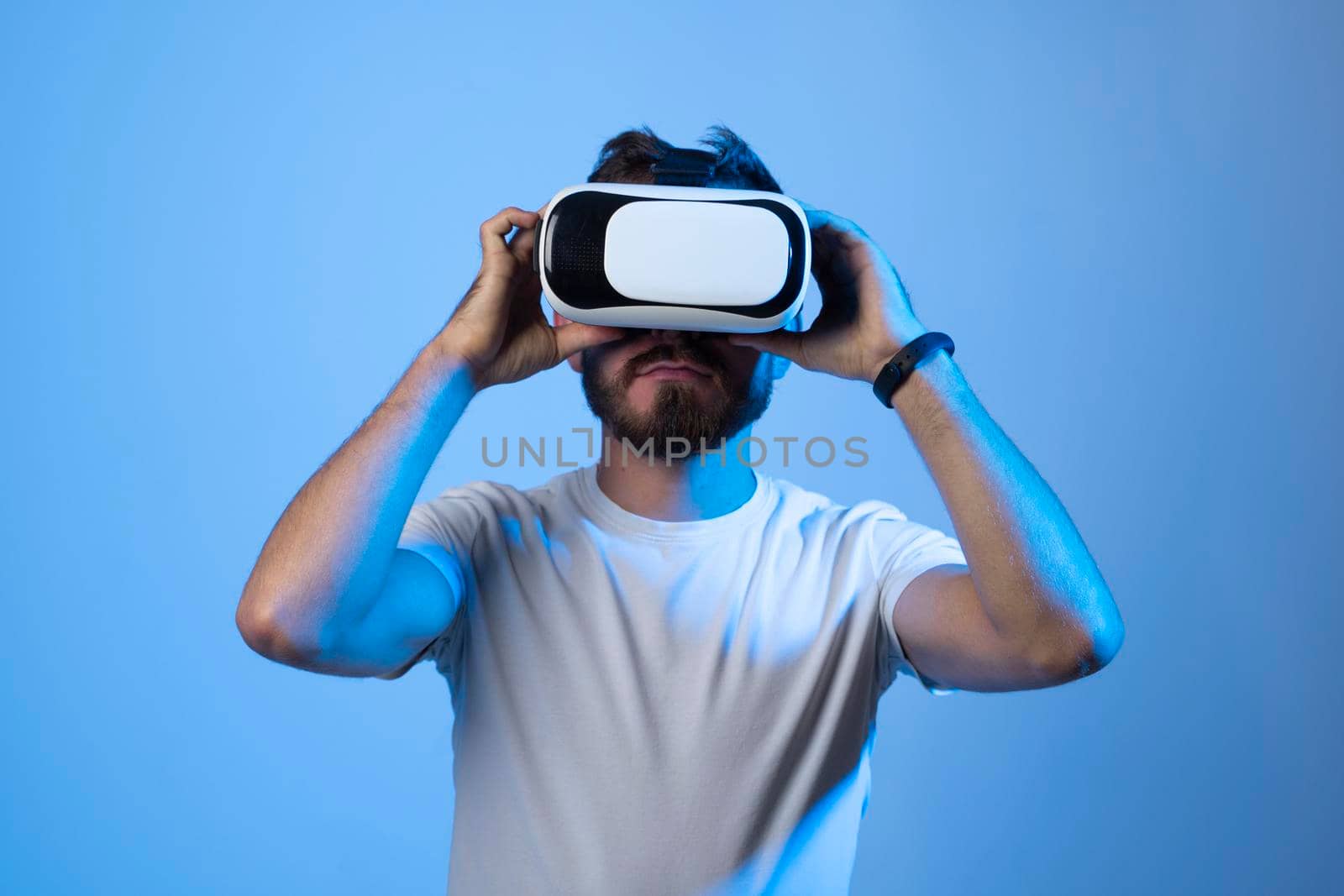 Future technology, gaming, entertainment and people concept - happy young man with virtual reality headset or 3d glasses playing video game in metaverse