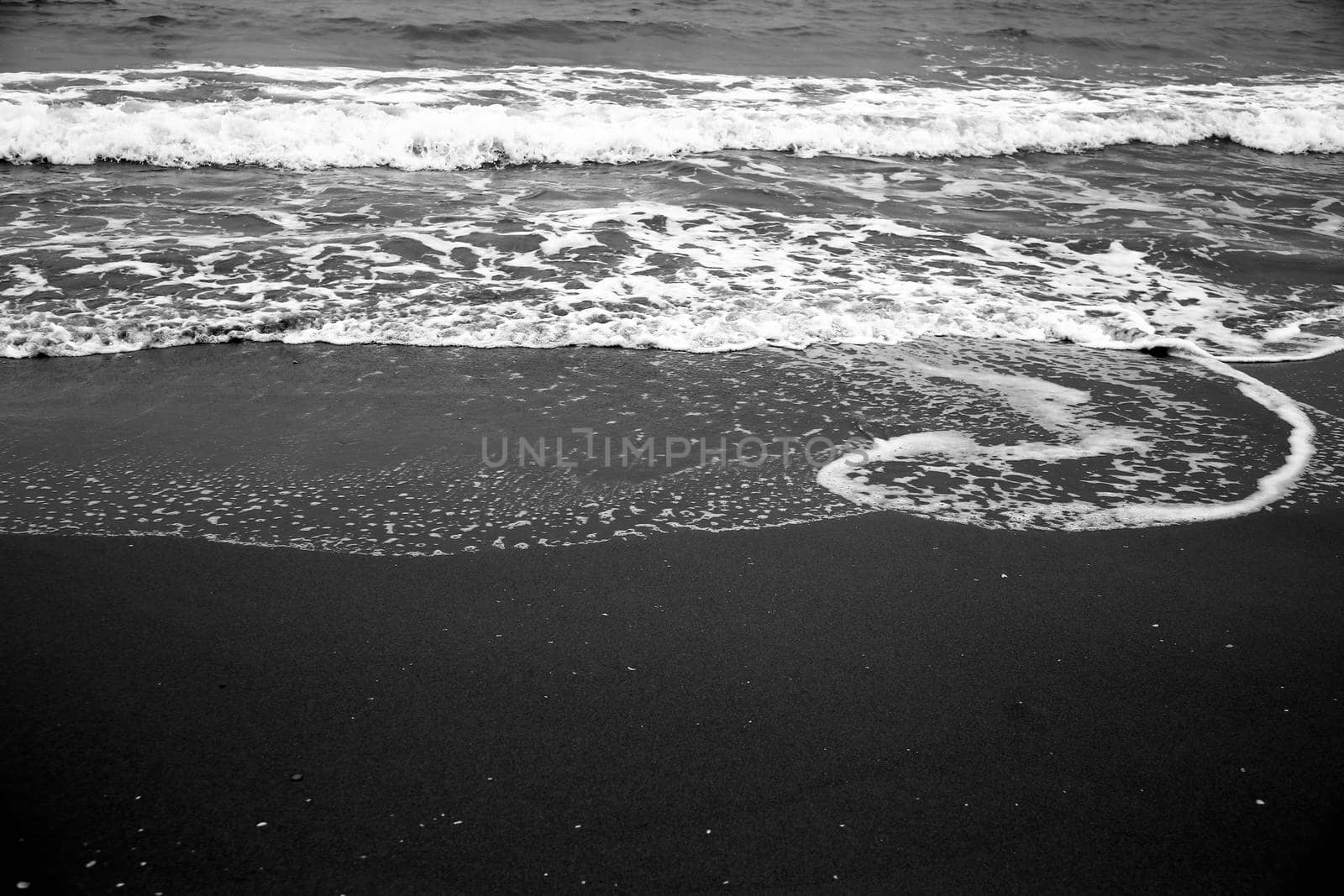 Waves drawing geometric shapes on the shore on La Marina beach, Alicante, Spain