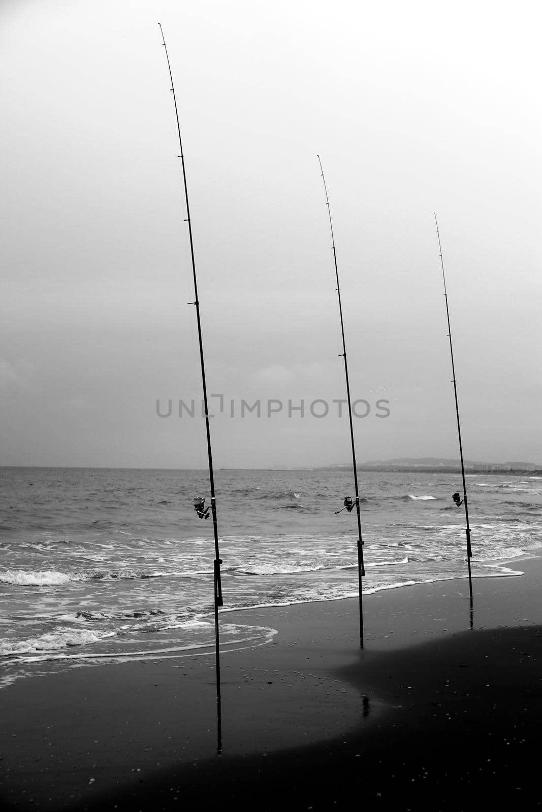 Fishing rods on the shore on a cloudy day on El Pinet Beach in Alicante, Spain