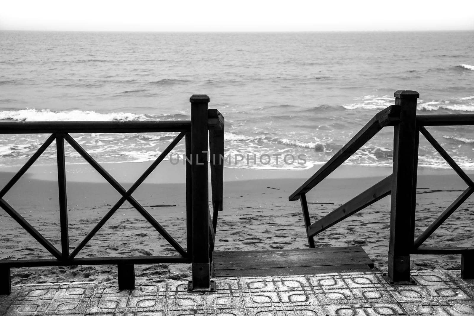 Wooden staircase to access the beach broken by the storm. Monochrome picture