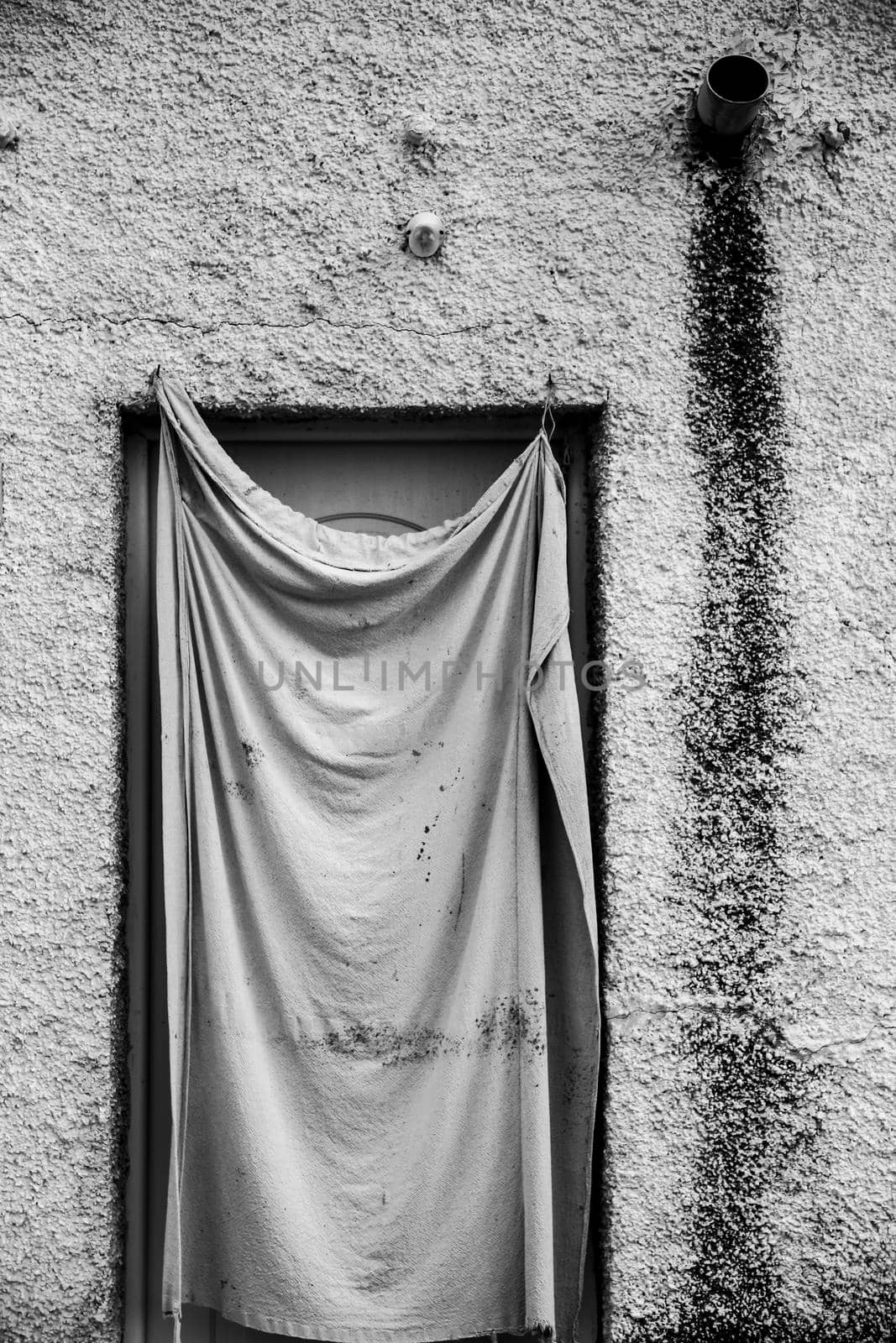 Facade in Spain with door protected by old cloth. Monochrome picture.
