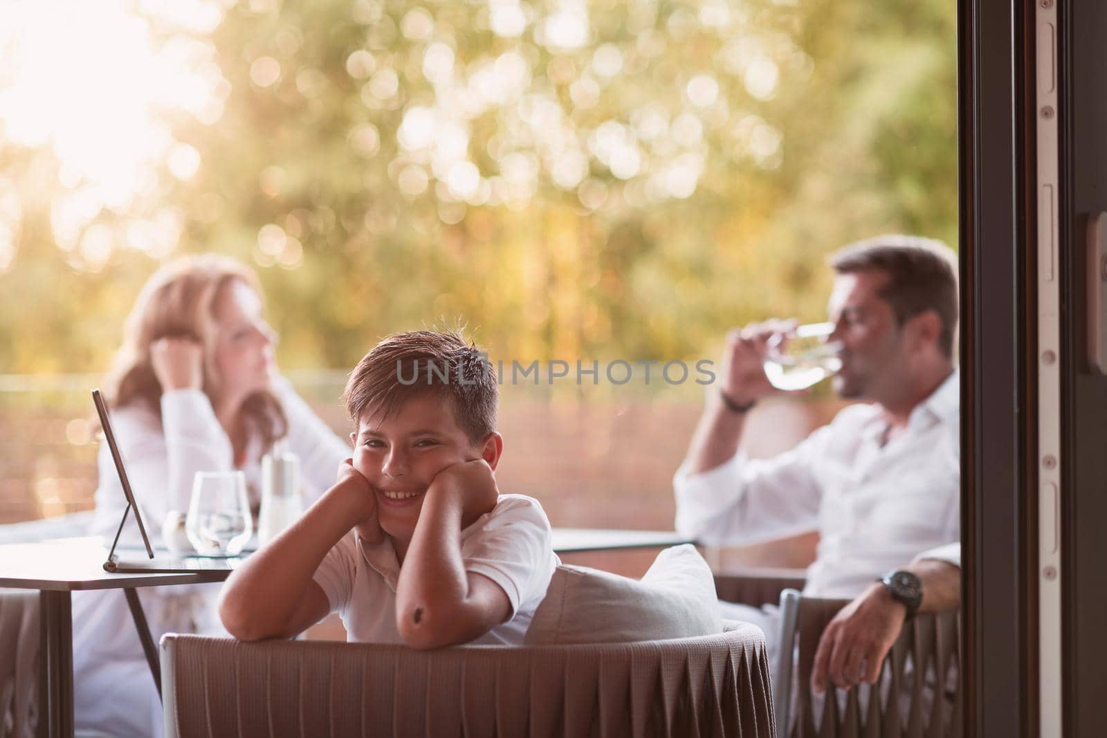 An elderly couple enjoys the terrace of a luxury house with their son during the holidays. Selective focus by dotshock