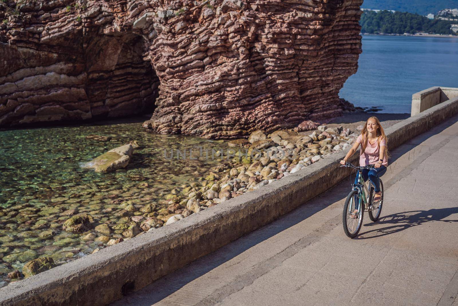 Woman tourist on a bicycle explores Budva in Montenegro. Cycling in Montenegro concept.