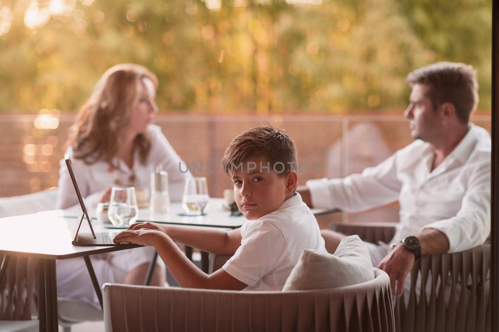 An elderly couple enjoys the terrace of a luxury house with their son during the holidays. Selective focus by dotshock