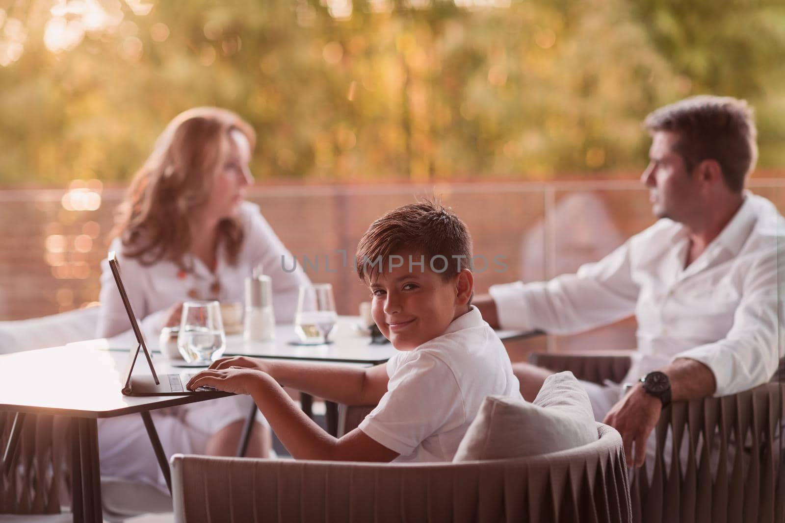 An elderly couple enjoys the terrace of a luxury house with their son during the holidays. Selective focus by dotshock