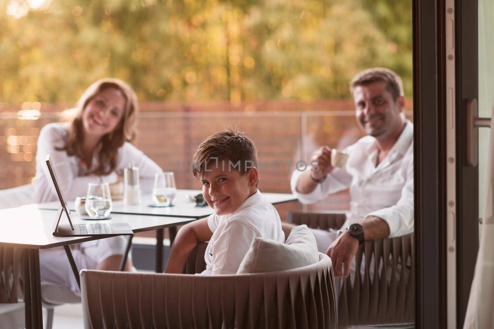 An elderly couple enjoys the terrace of a luxury house with their son during the holidays. Selective focus. High-quality photo