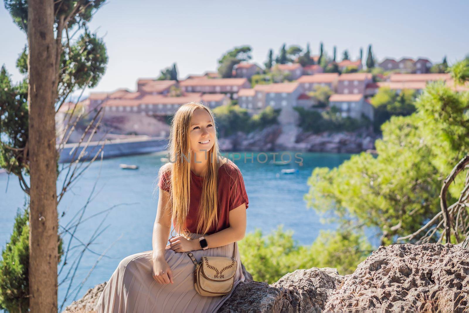 Woman tourist on background of beautiful view of the island of St. Stephen, Sveti Stefan on the Budva Riviera, Budva, Montenegro. Travel to Montenegro concept.