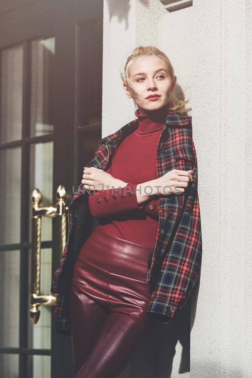 fashionable blonde girl with a red lipstick posing outdoors . Dressed in a red leather leggings, turtleneck and checkered jacket. fit figure by Ashtray25