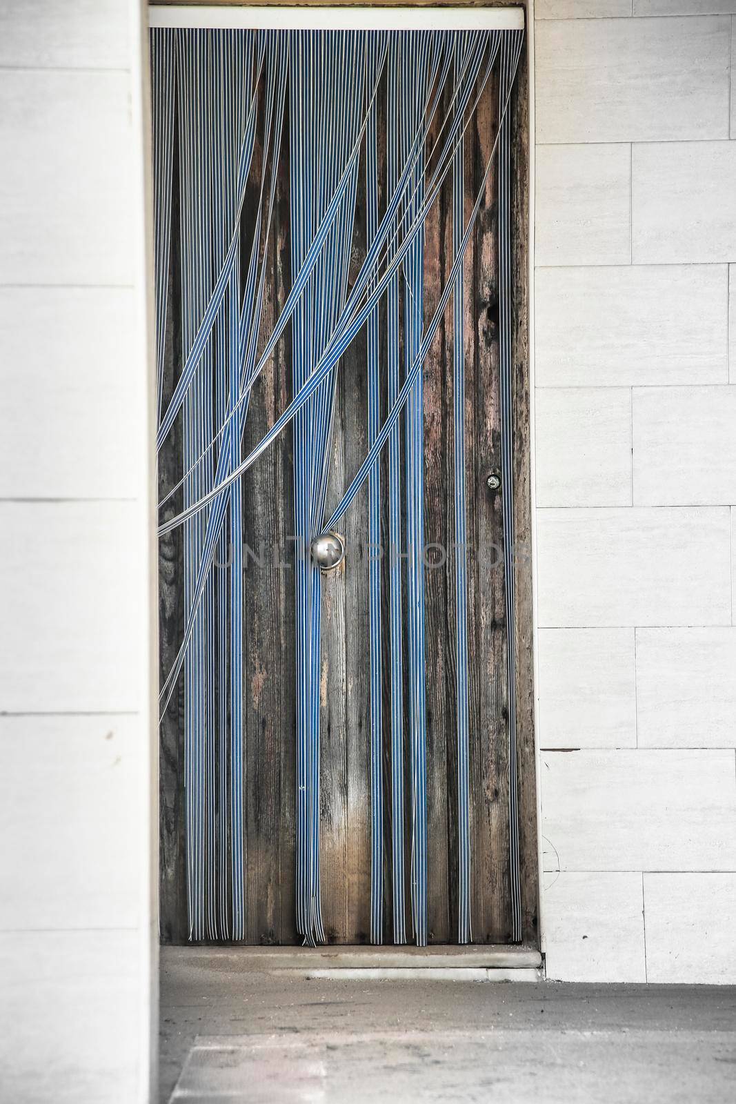 Wooden door with striped plastic curtain by soniabonet