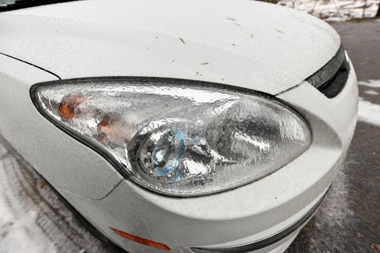 Freezing Rain Creates a Layer of Ice and Coats a Passenger Vehicle. Close up of Headlights. High quality photo