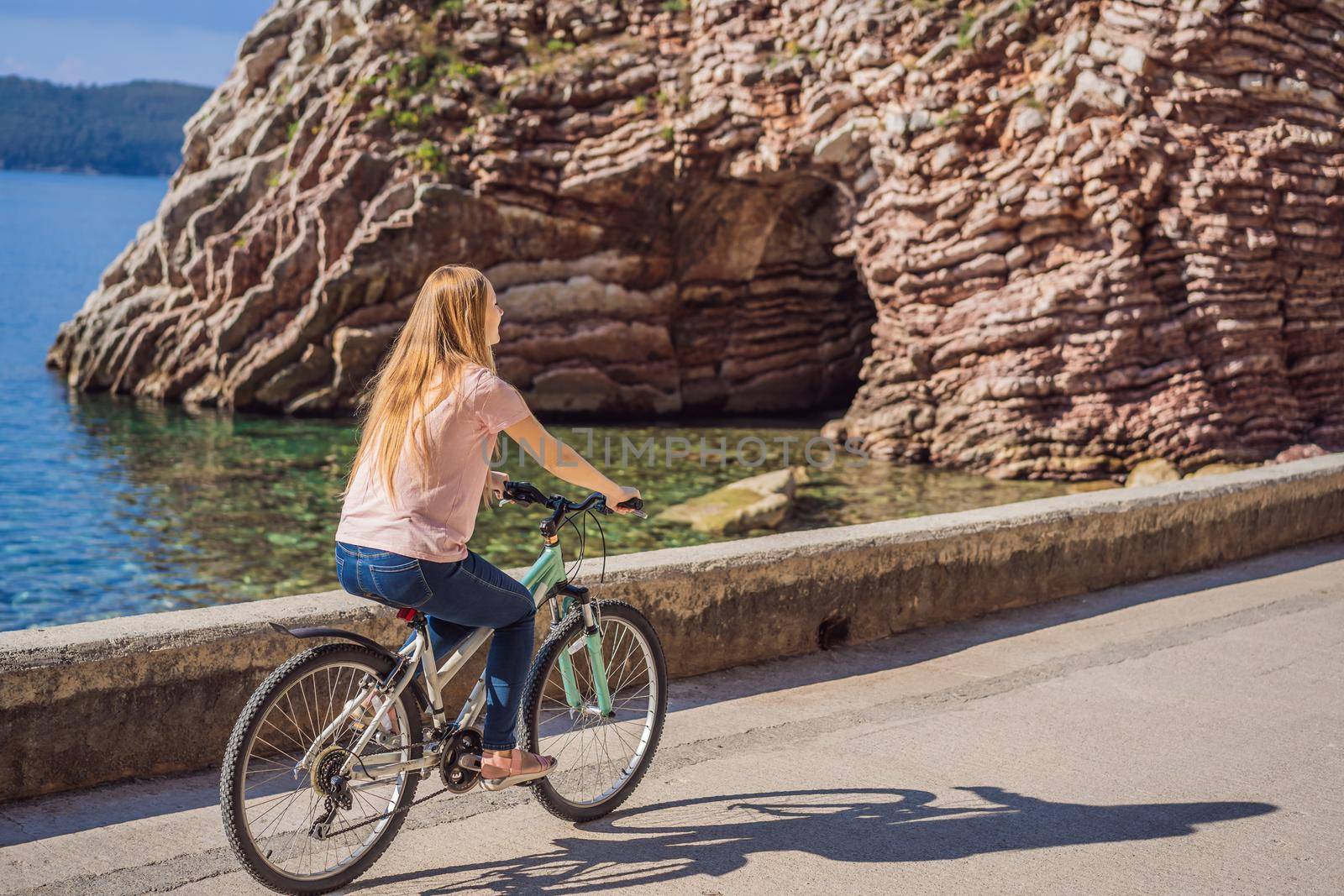 Woman tourist on a bicycle explores Budva in Montenegro. Cycling in Montenegro concept.