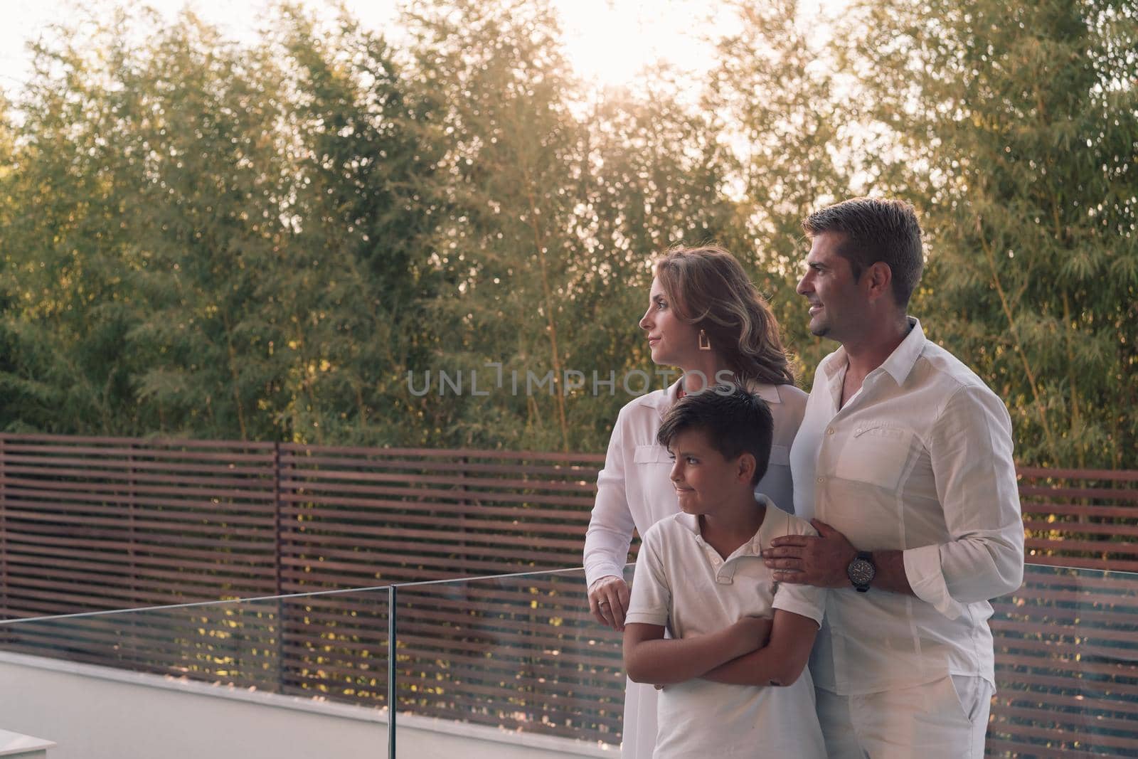 Happy family resting on the balcony of a luxury house surrounded by forest nature. Selective focus by dotshock